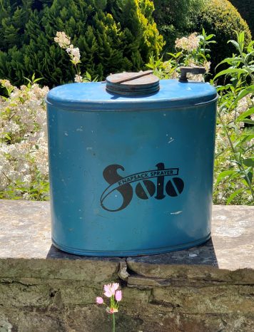 A Decorative Blue Metal Knapsack Sprayer With Straps